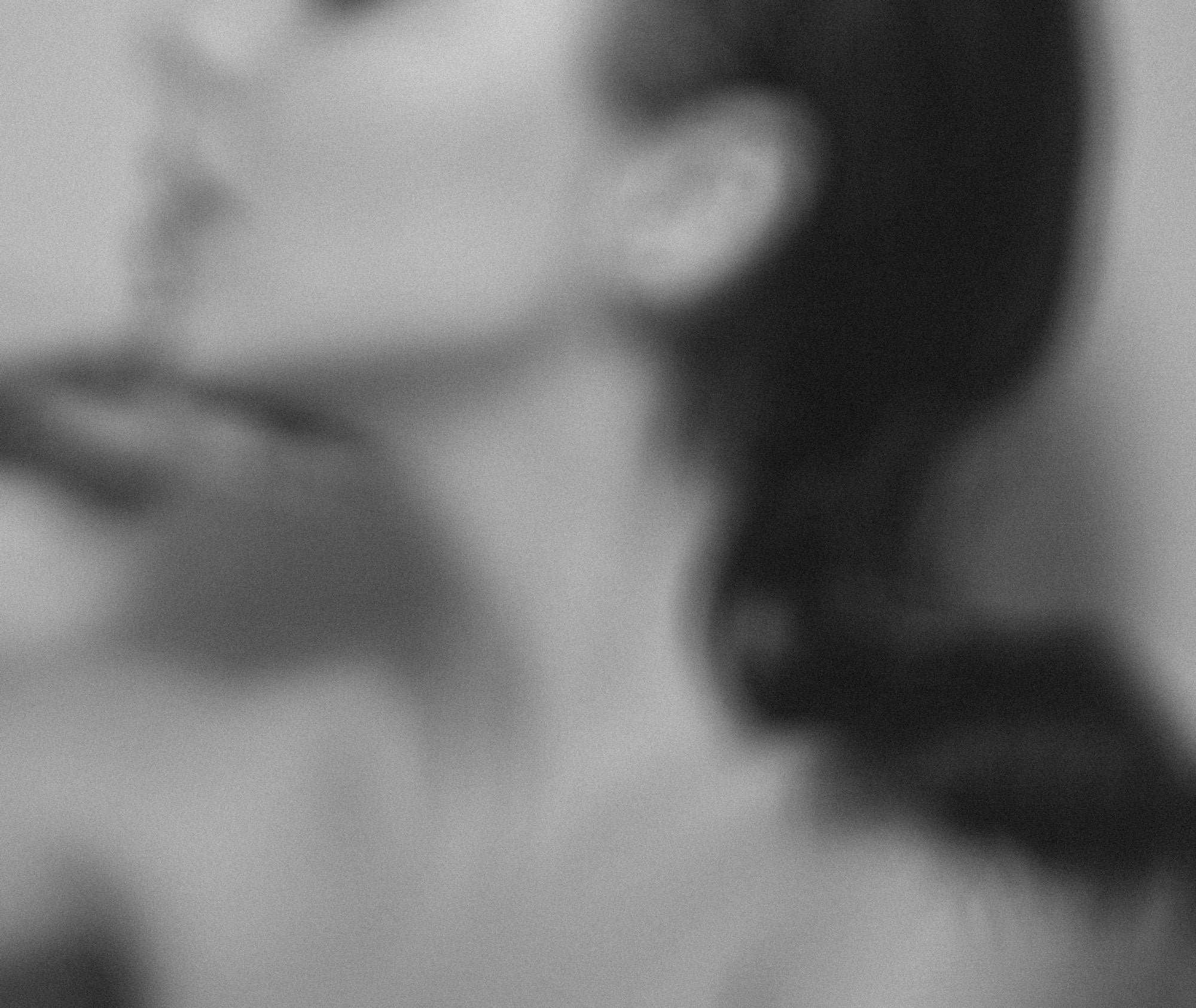 Blurry black and white image of brunette woman looking towards her left.